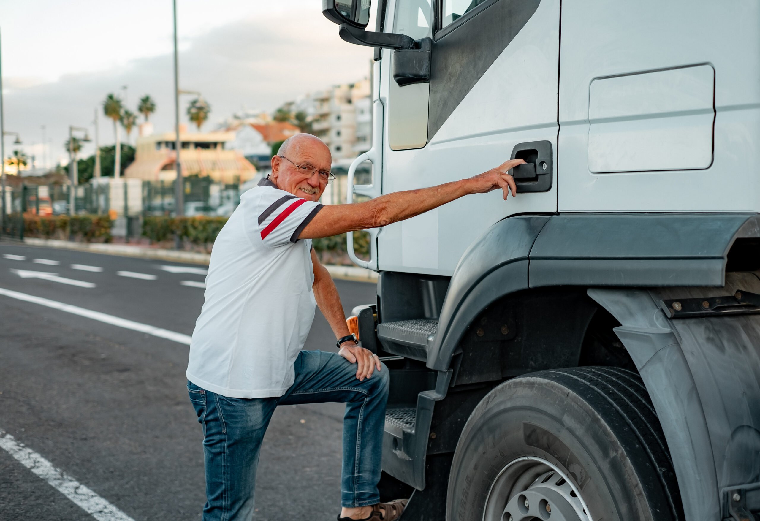 Senior truck driver prepares to climb into the cab of his truck.