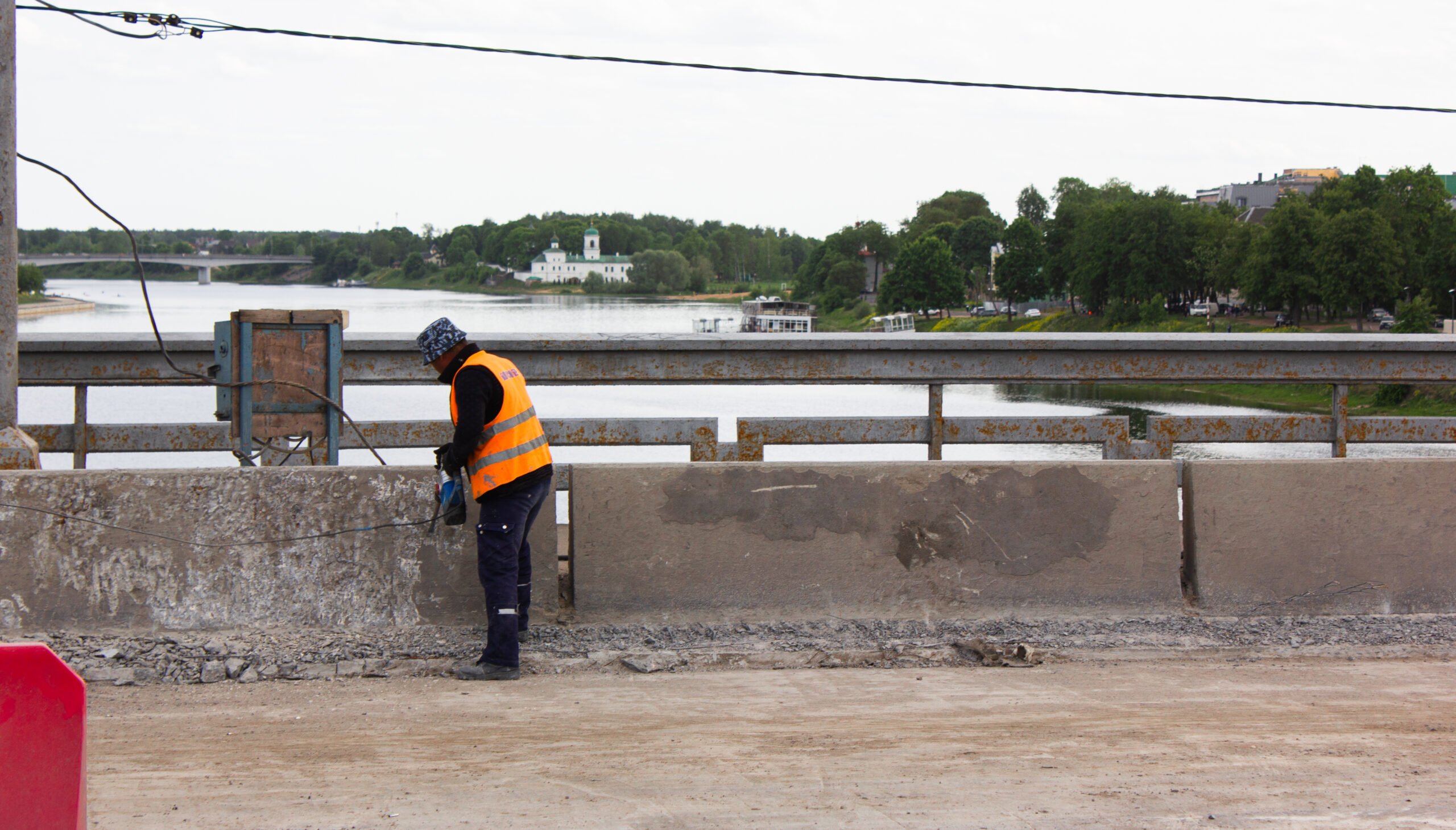 Repair, restoration of the road on the bridge, the worker is repairing the highway on the bridge.Men at work. Repair of curbs on the highway.
